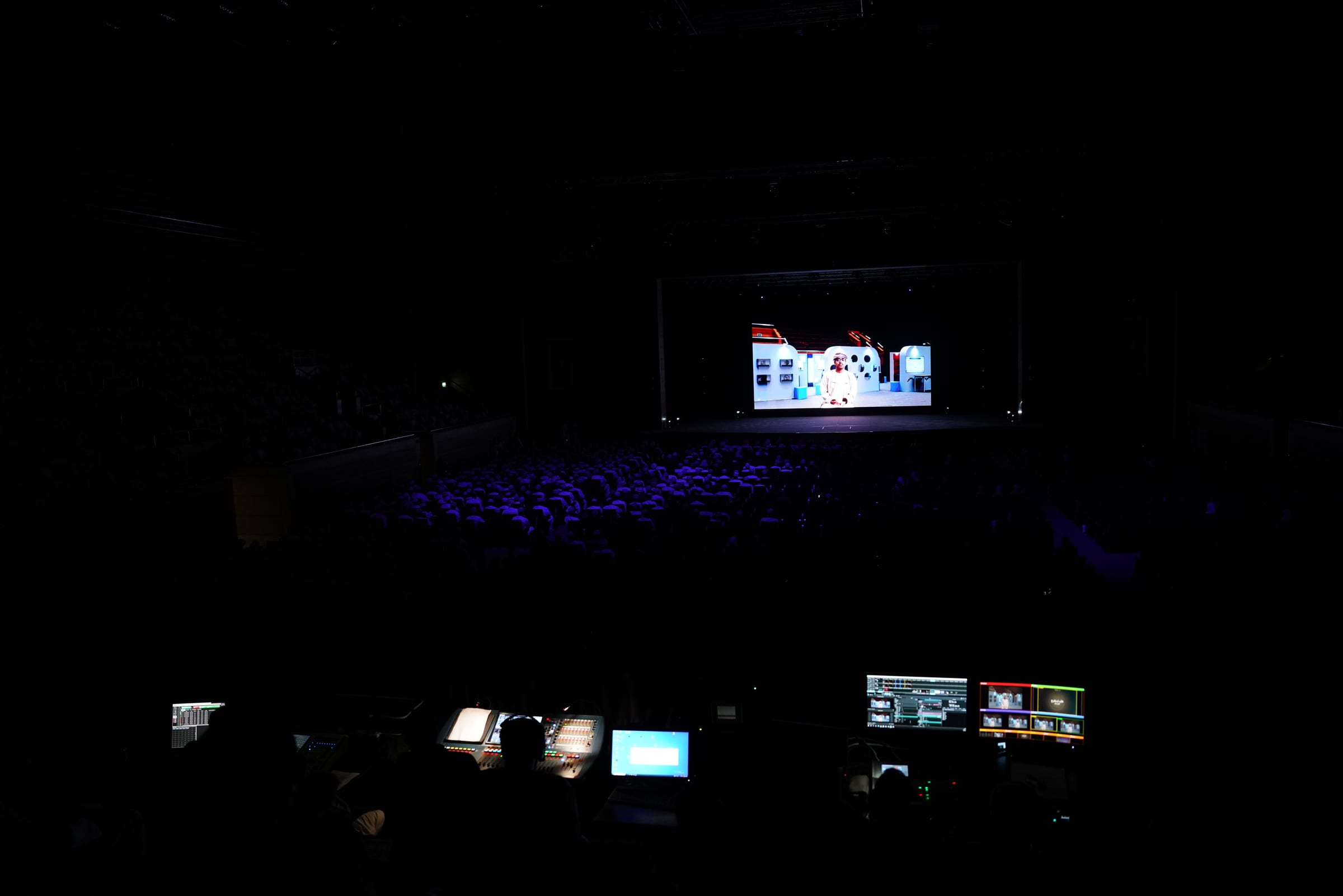 The closing evening seen from the control desk: a dark hall, the audience and the lit stage screen.